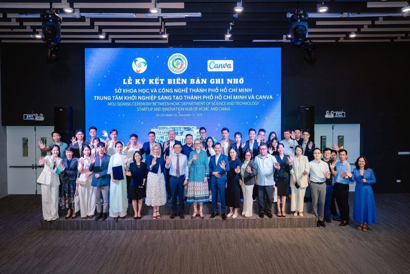 Ảnh lưu niệm tập thể dưới backdrop lễ ký kết biên bản ghi nhớ với Canva