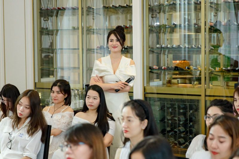 Vũ Hà Trang cầm micro phía sau hàng khán giả nữ tại live event Queens Academy
