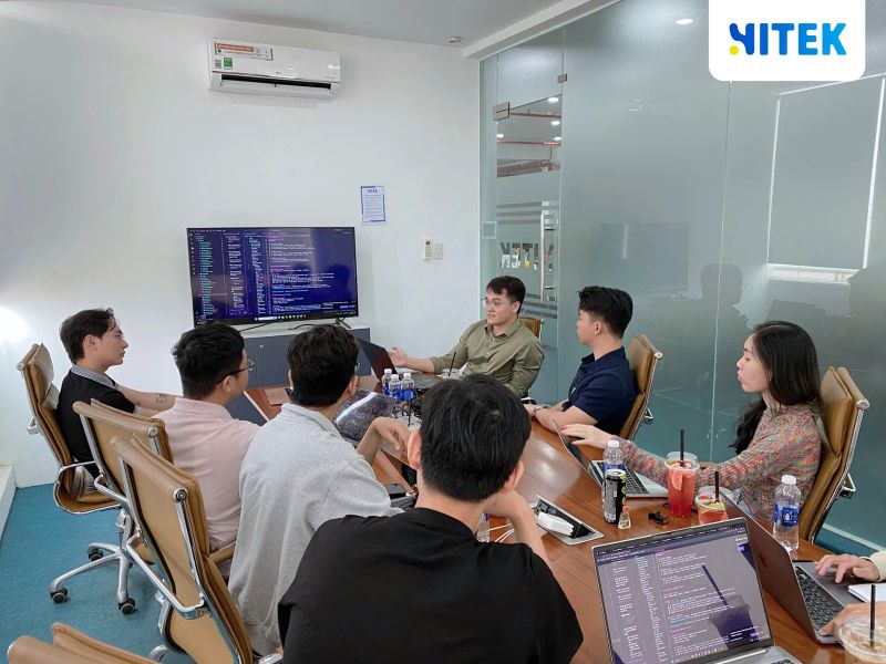 Toàn cảnh phòng họp Hitek Software, màn hình lớn hiển thị một coding agent đang chạy trên dòng lệnh
